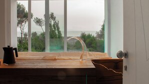 A modern kitchen with a large window, a coffee maker, and a wooden countertop.