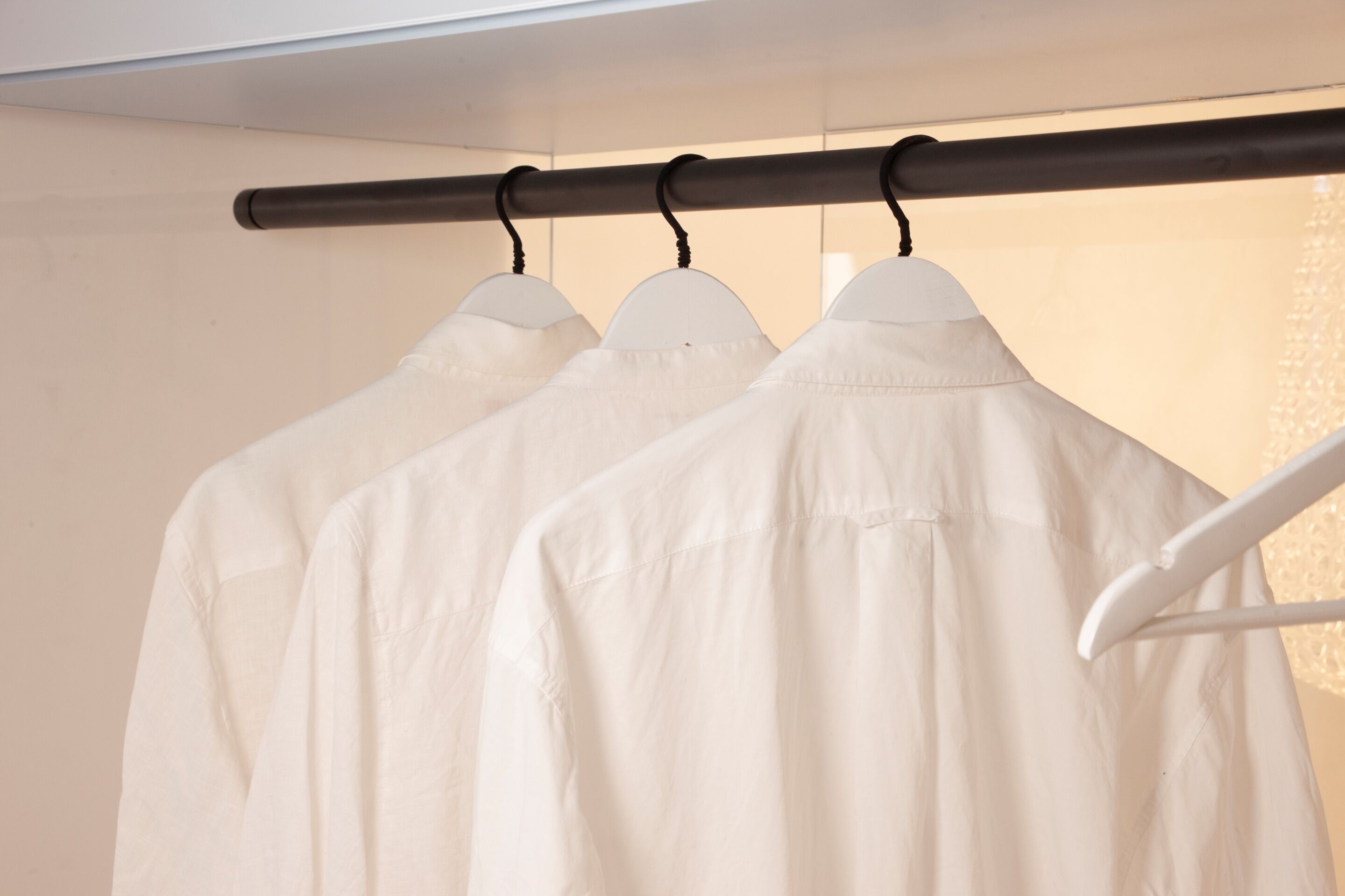 Un portant à vêtements sur lequel sont suspendues plusieurs chemises blanches.