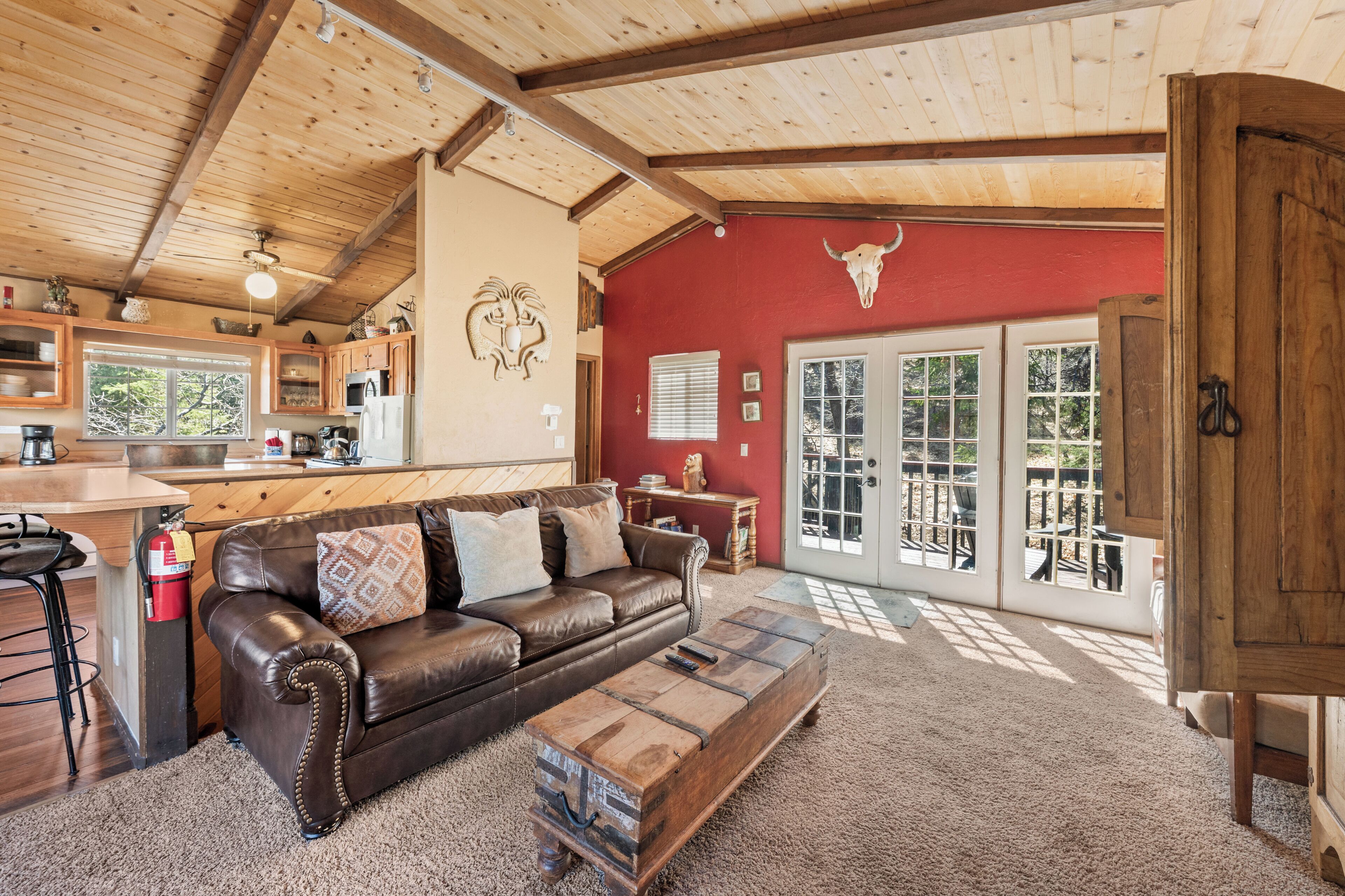 A cozy living room with a leather sofa, a coffee table, and a red wall with a bull's head decoration.