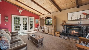 A living room with a fireplace, leather sofa, and a red wall.