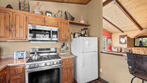 A kitchen with wooden cabinets, stainless steel appliances, and a wooden ceiling.