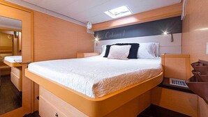 A bedroom with a bed, bedside tables, a mirror, and a headboard with a sign. - Cocoloco - Catamaran Lagoon 52F SAN BLAS (Narganá)