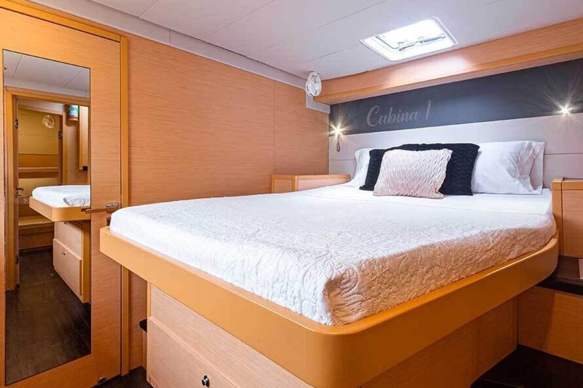 A bedroom with a bed, bedside tables, a mirror, and a headboard with a sign.