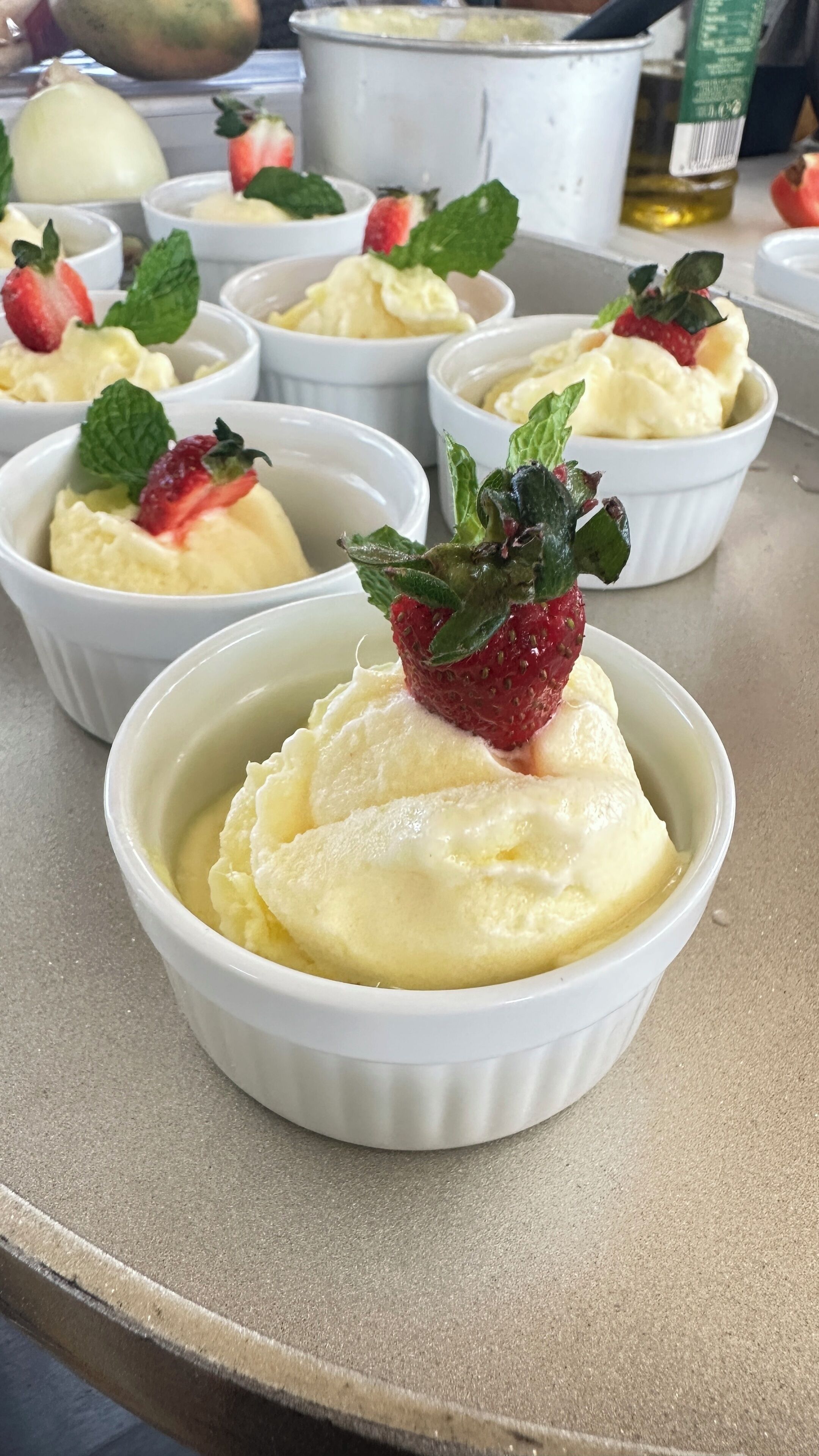 Un présentoir de desserts avec des portions individuelles de crème glacée, garnies de fraises et de feuilles de menthe.