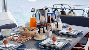 A table set for breakfast on a boat with various food items, condiments, and a view of the sea. - Cocoloco - Catamaran Lagoon 52F SAN BLAS (Narganá)