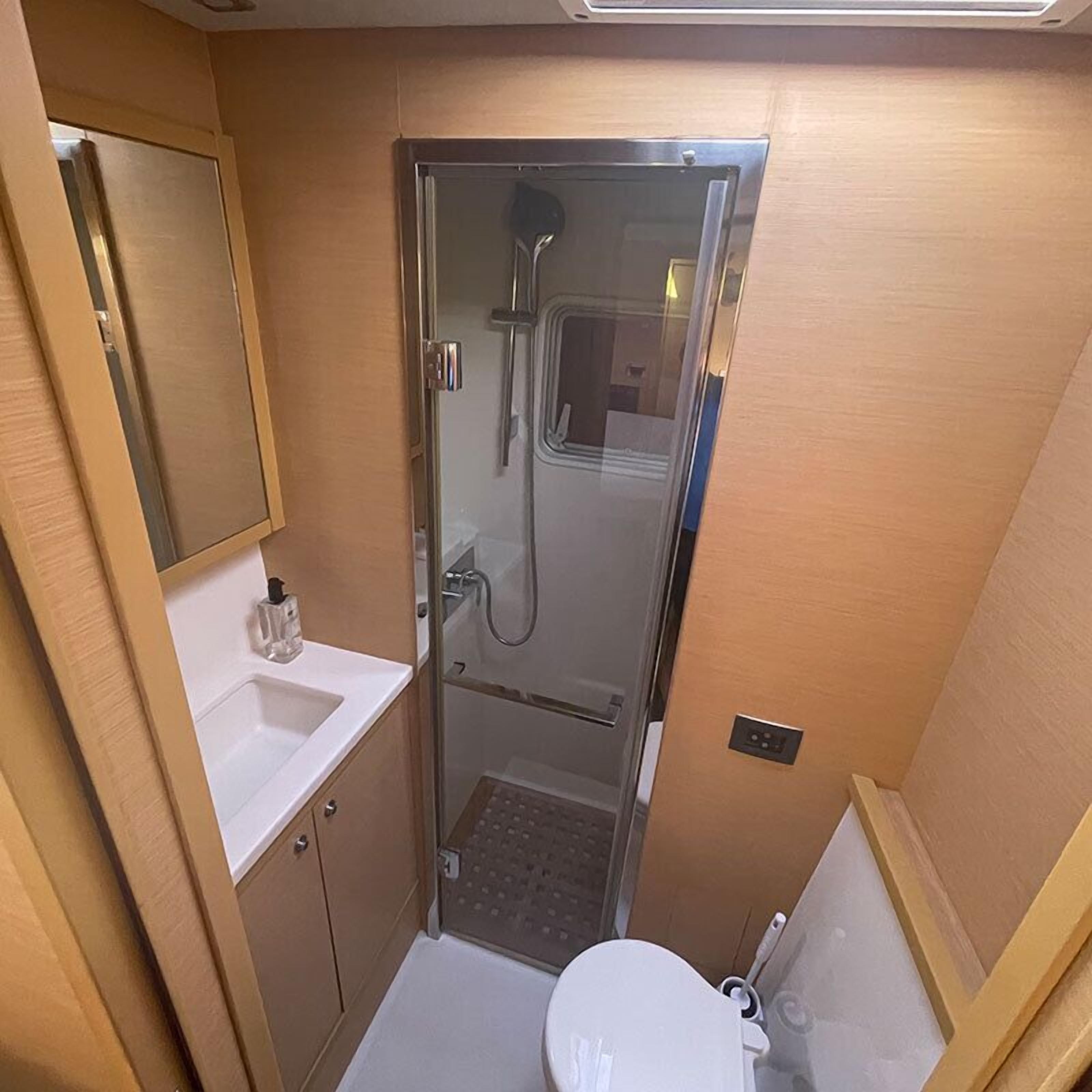 Un baño pequeño con cabina de ducha de vidrio, lavamanos blanco y un inodoro.