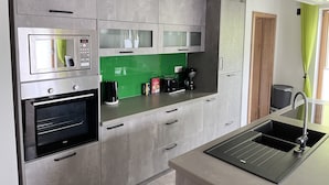 Una cocina moderna con electrodomésticos integrados, un salpicadero verde y un lavamanos de acero inoxidable.