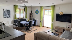 Una sala de estar moderna con comedor, televisor de pantalla plana en la pared y sofá.