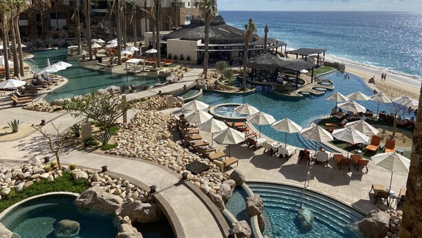 Un complexe hôtelier doté de plusieurs piscines, d’espaces de plage et d’un grand bâtiment avec des balcons.
