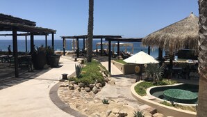Un complexe hôtelier situé en bord de mer, doté d’une terrasse, d’une piscine et offrant une vue sur l’océan.