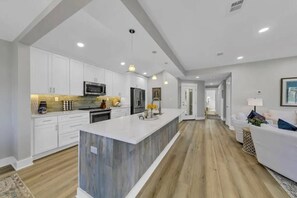 A modern kitchen with white cabinetry, a wooden island, and a central island with a sink. - 3 bed 3 bath beach and bay escape - Free golf cart (Destin)