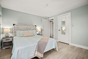 Relax in this serene bedroom with a large bed, bedside tables, and a cozy duvet.