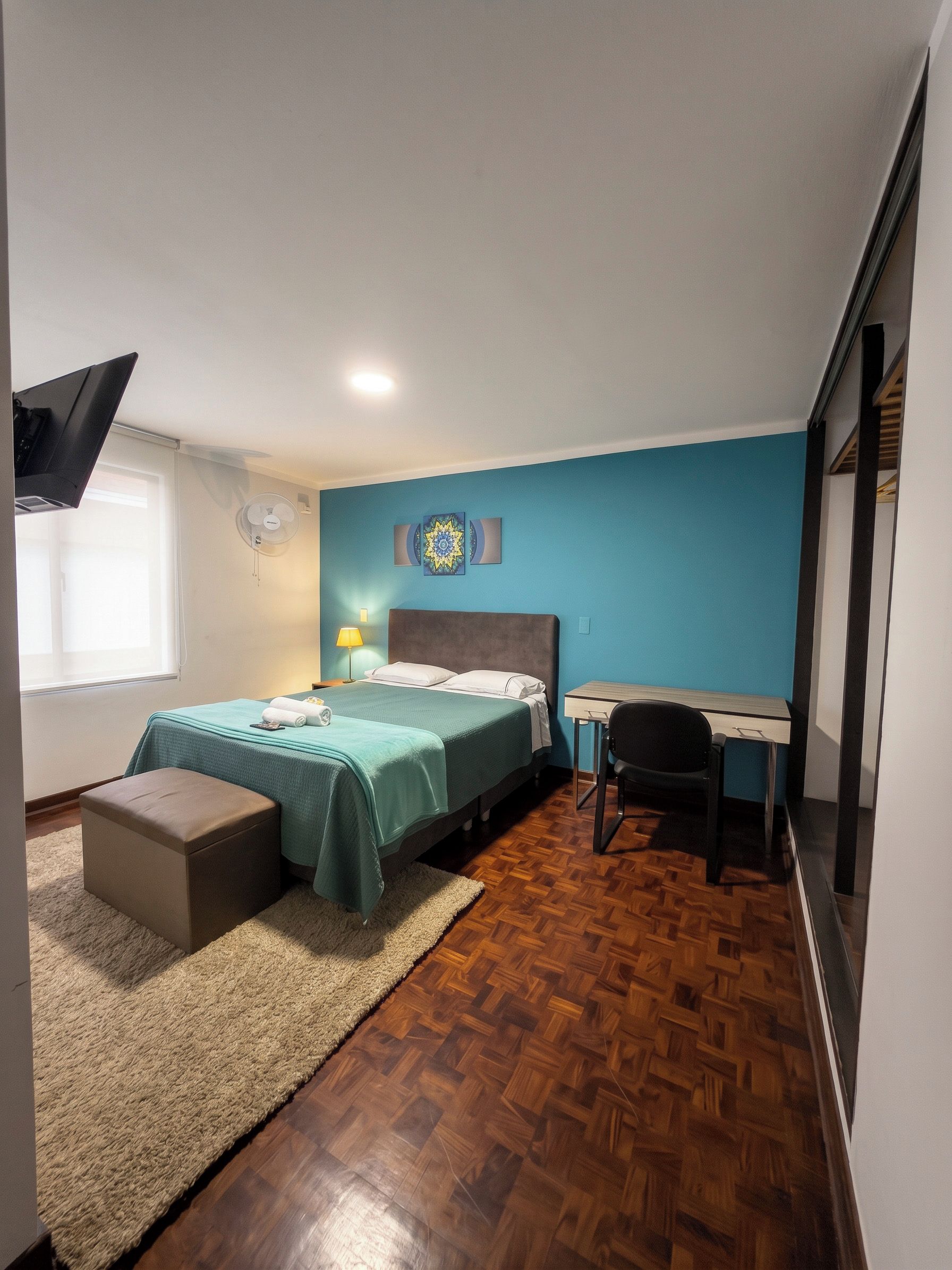 Une chambre à coucher avec un lit, un bureau, une chaise et une fenêtre.