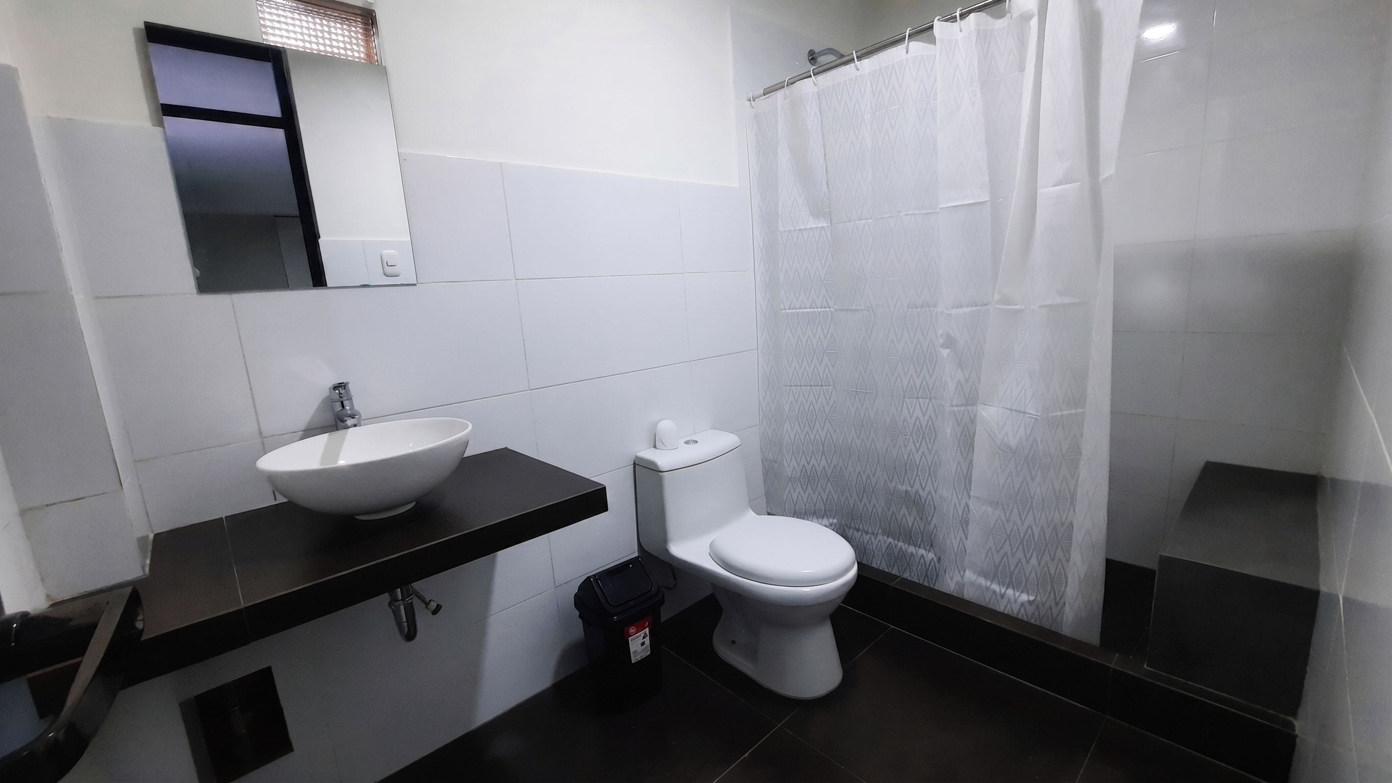 Un baño con lavamanos, inodoro y cortina de ducha blanca.