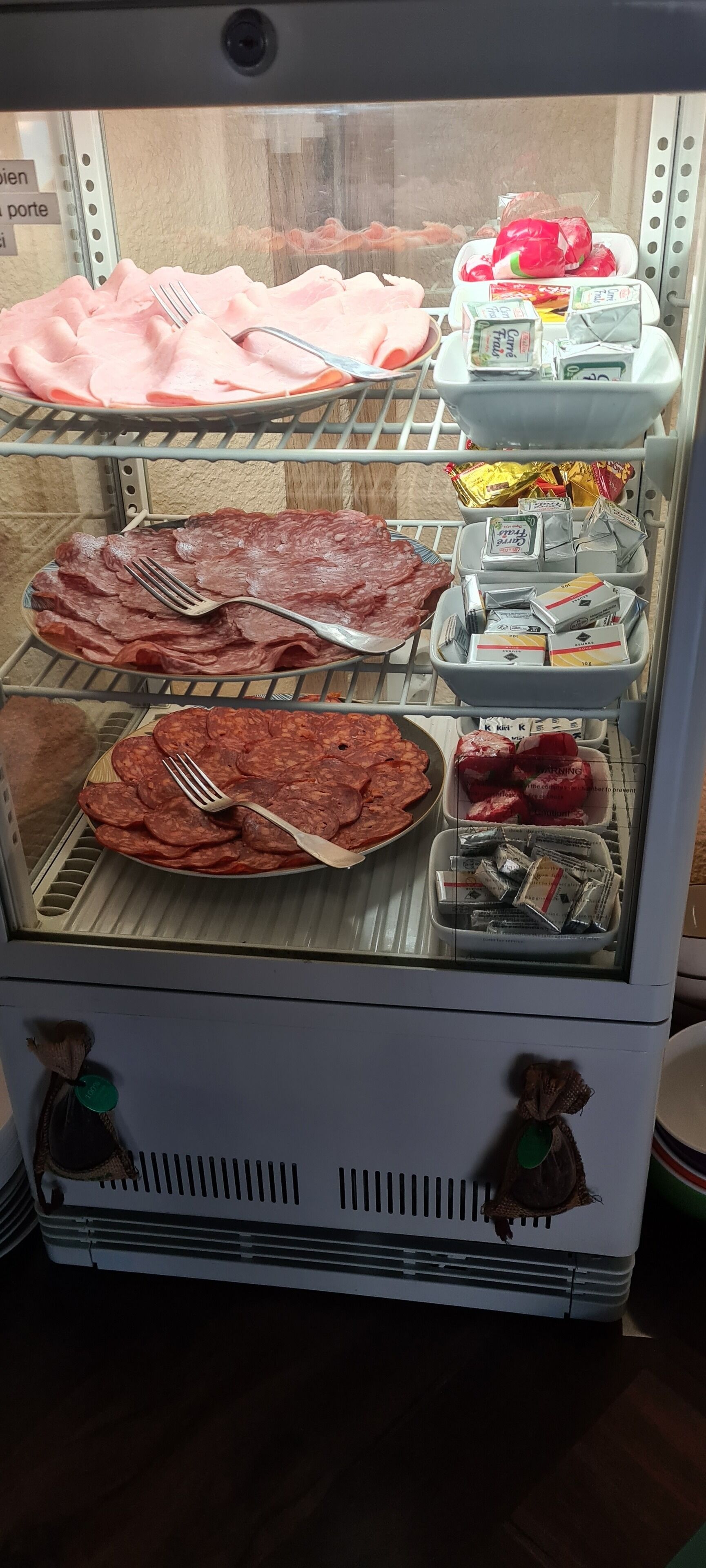 A deli display case with various meats and condiments.