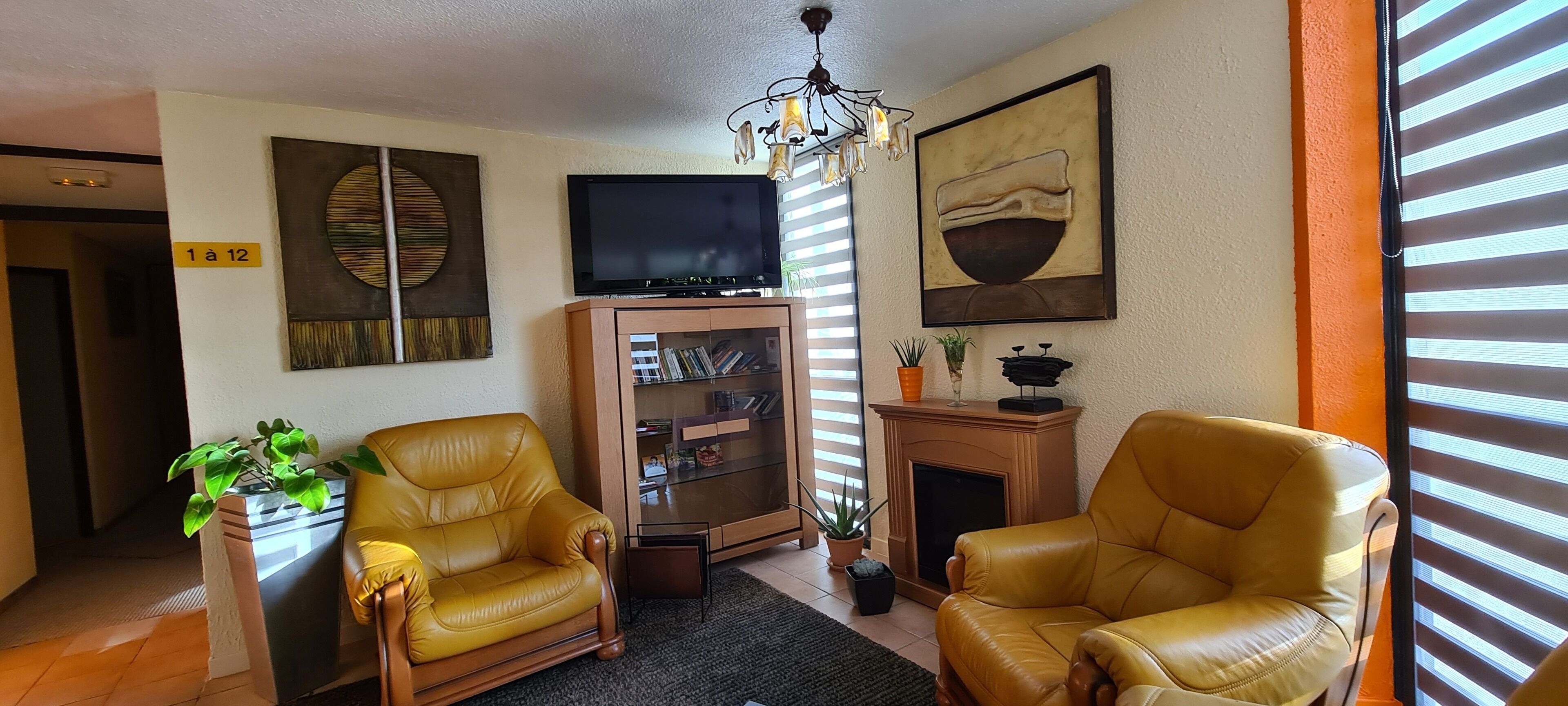 A living room with two leather chairs, a television, a cabinet with books, and a fireplace.