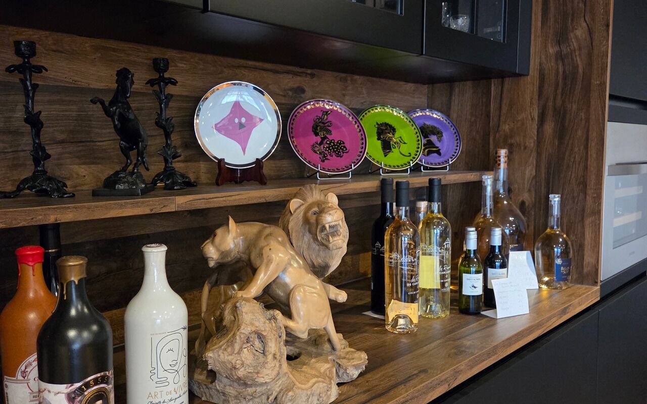 A wooden shelf with decorative plates, wine bottles, and a lion sculpture.