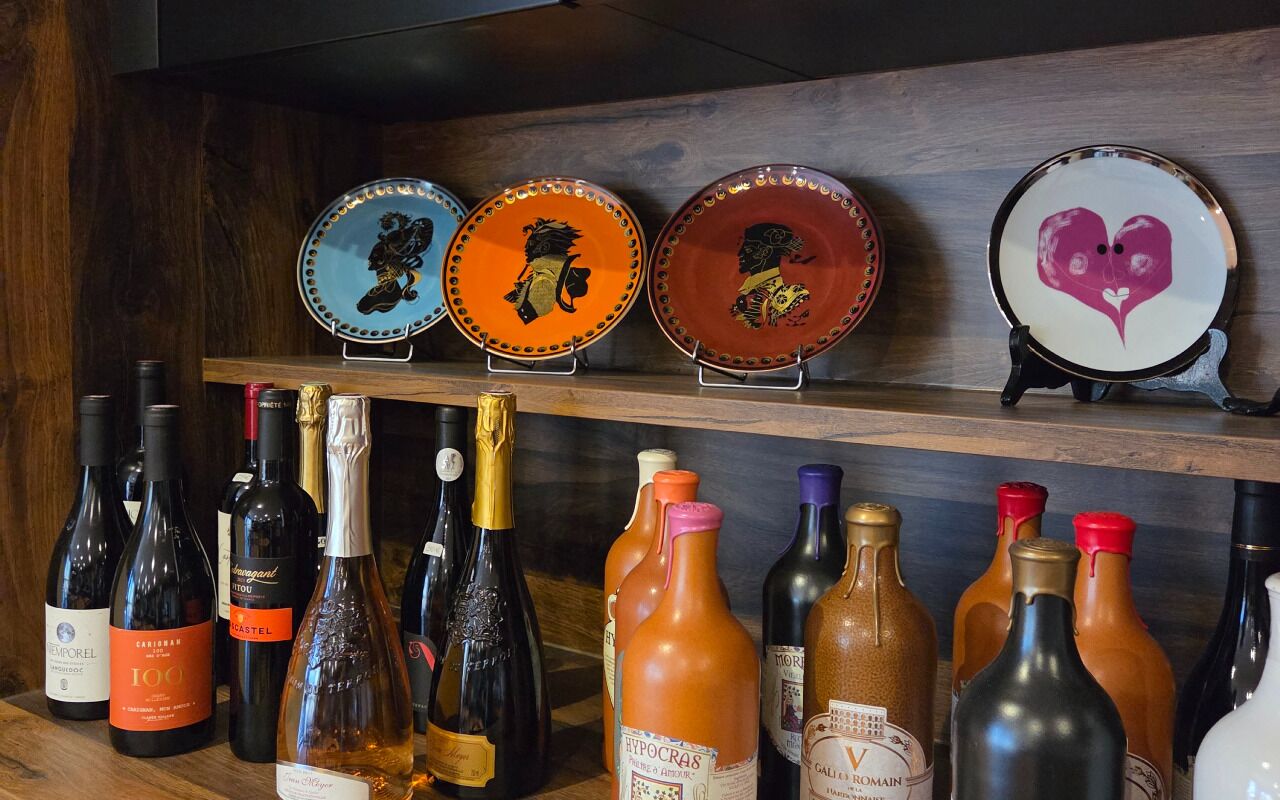 Uma estante para vinhos com várias garrafas e pratos decorativos.