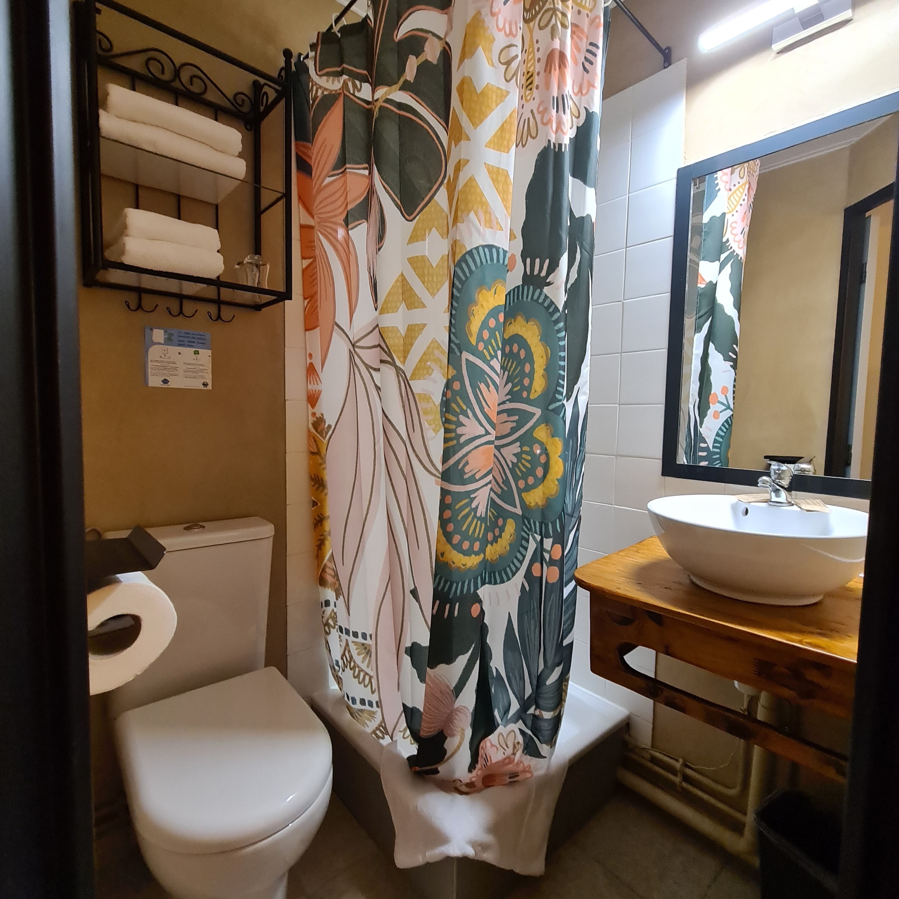 A bathroom with a toilet, a sink, a shower curtain, and a towel rack.