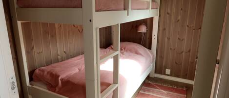 A bunk bed room with a wooden floor and a striped rug.