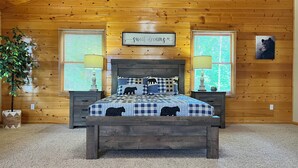 A cozy bedroom with a wooden headboard, a quilted bedspread, and a sign above the bed that reads "sweet dreams".