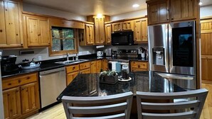 A modern kitchen with wooden cabinets, stainless steel appliances, and a central island with chairs.