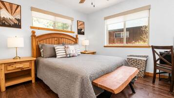 A bedroom with a bed, bedside tables, a bench, a chair, and a ceiling fan.