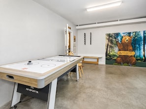 Una habitación con una mesa de fútbol de mesa, un banco y un mural de un oso.