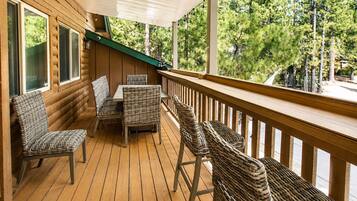 A wooden deck with wicker furniture and a view of trees.