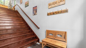 Una escalera de madera con un banco de madera y decoraciones en la pared, incluyendo un letrero que dice Big Bear Lake.