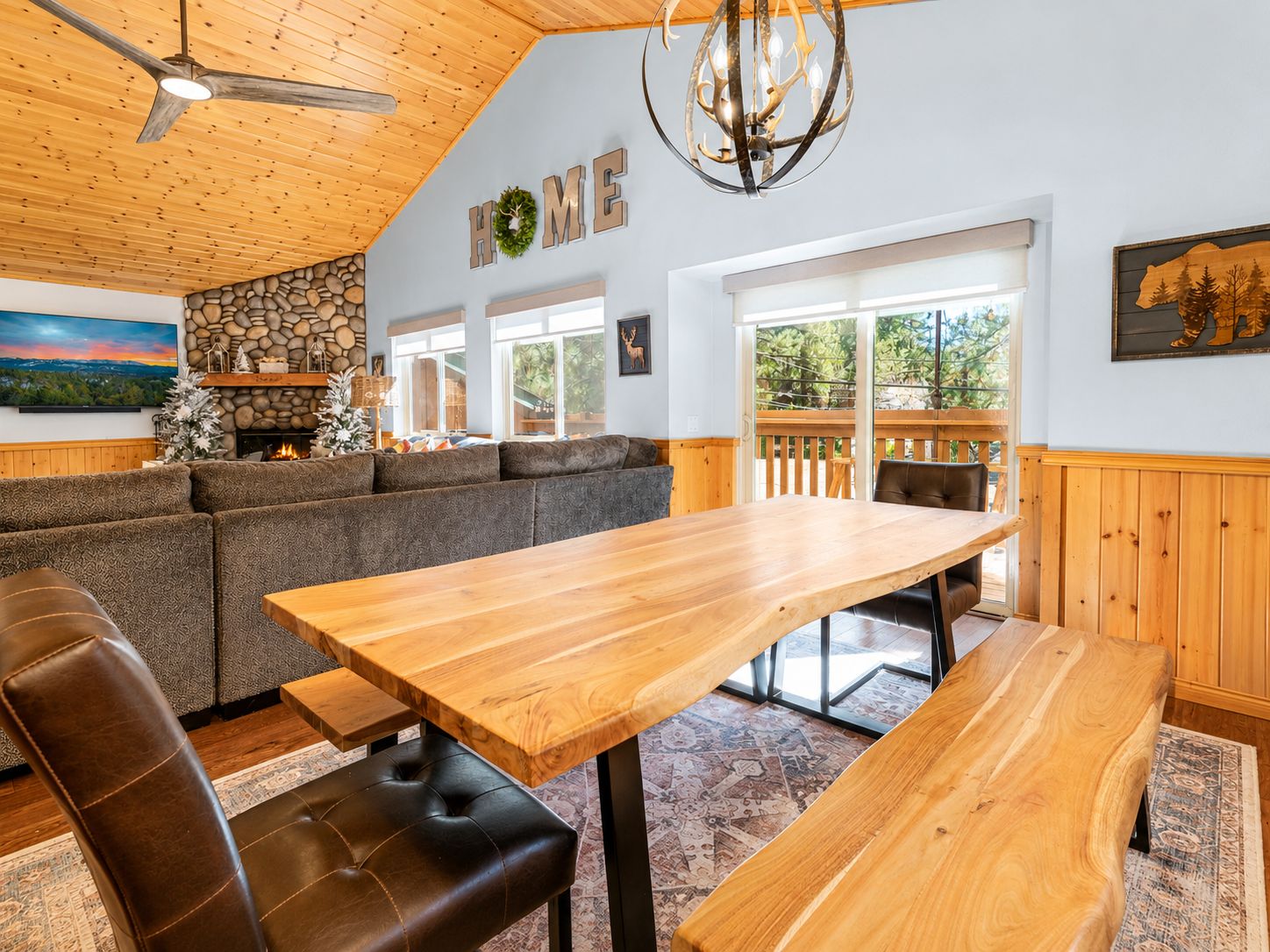 Un interior acogedor con techo de madera, chimenea de piedra, una amplia mesa de comedor de madera y un espacio de descanso confortable.