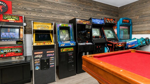 Een pooltafel met speelautomaten in een ruimte met houten wanden.