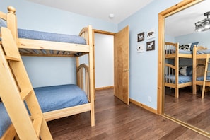 Una habitación con una cama litera, una escalera, una puerta y un espejo que refleja otra cama litera.