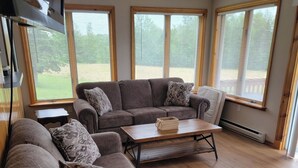 A living room with a sectional sofa, a coffee table, and large windows.