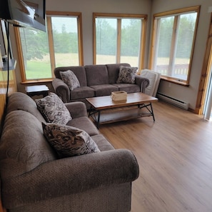 A living room with a sectional sofa, a coffee table, and large windows.