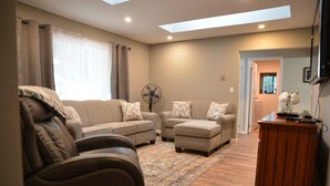 A living room with a sofa set, a fan, and a wooden cabinet.