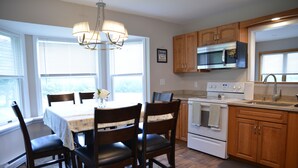 A kitchen with wooden cabinets, a white stove, and a dining table with chairs.