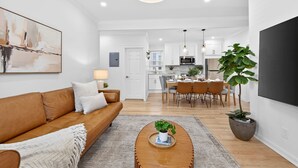 A modern living room with a sofa, coffee table, and artwork. - Open 4BR Near Downtown Boston Backyard, Fire Pit, Grills & Walk to Train (Boston)