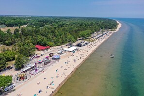 An aerial view of a beach with a long stretch of sand, a few umbrellas, and a few people. - 4BR River Retreat: Beach, Boat, Sunsets, Wildlife, Spacious & Serene Escape (Two Rivers)