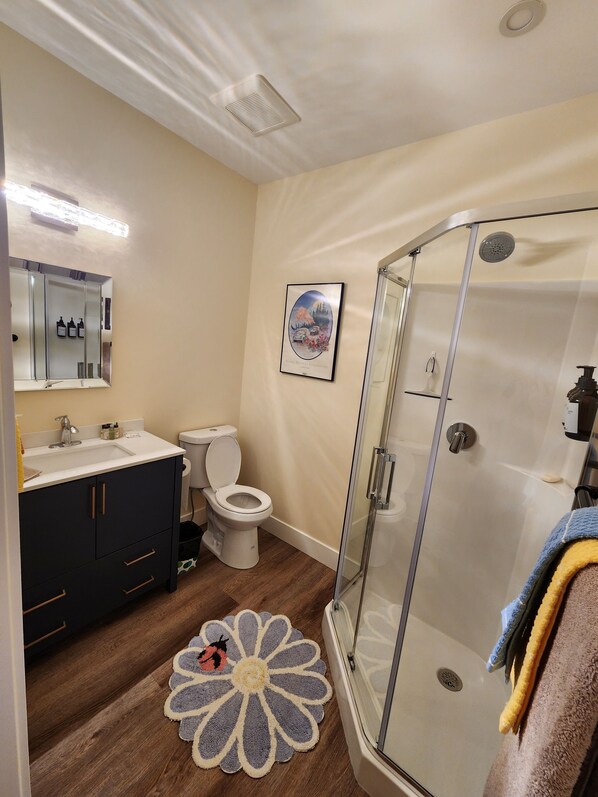 A bathroom with a shower, toilet, sink, and dark cabinets. - RELAX, REJUVENATE, PLAY!! (Armstrong)