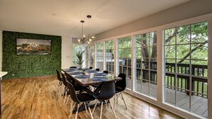 A dining area with a wooden table, black chairs, and a green wall with a picture. - Modern! 4BR, Game Room, Pets, Hot Tub, PS5, 6 min to Dollywood + More! Sleeps 8! (Pigeon Forge)