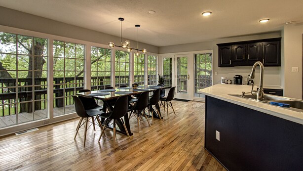 A spacious kitchen with a large island, dark cabinetry, and a view through large windows to a deck. - Modern! 4BR, Game Room, Pets, Hot Tub, PS5, 6 min to Dollywood + More! Sleeps 8! (Pigeon Forge)