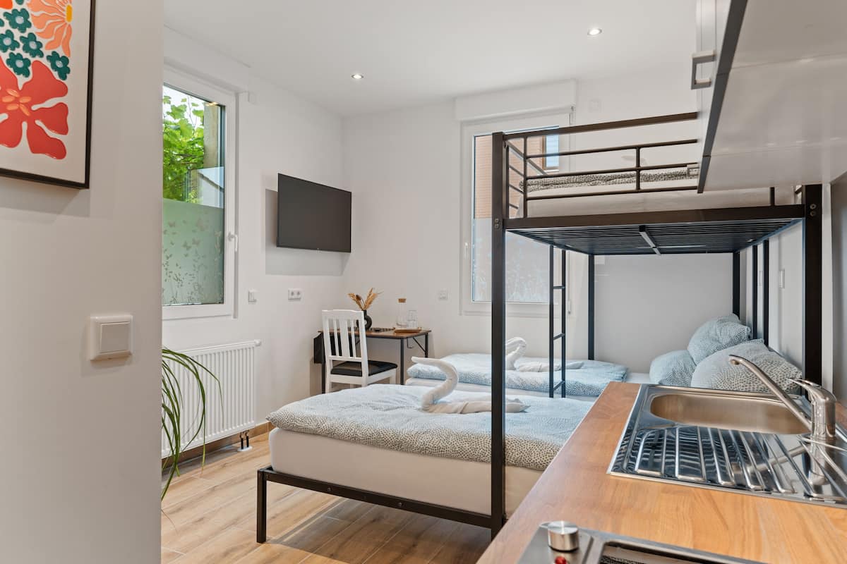 A modern, well-lit room with a bunk bed, a desk, a chair, and a large window.