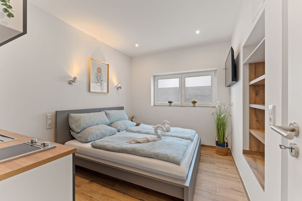 A modern bedroom with a bed, bedside table, and a window.