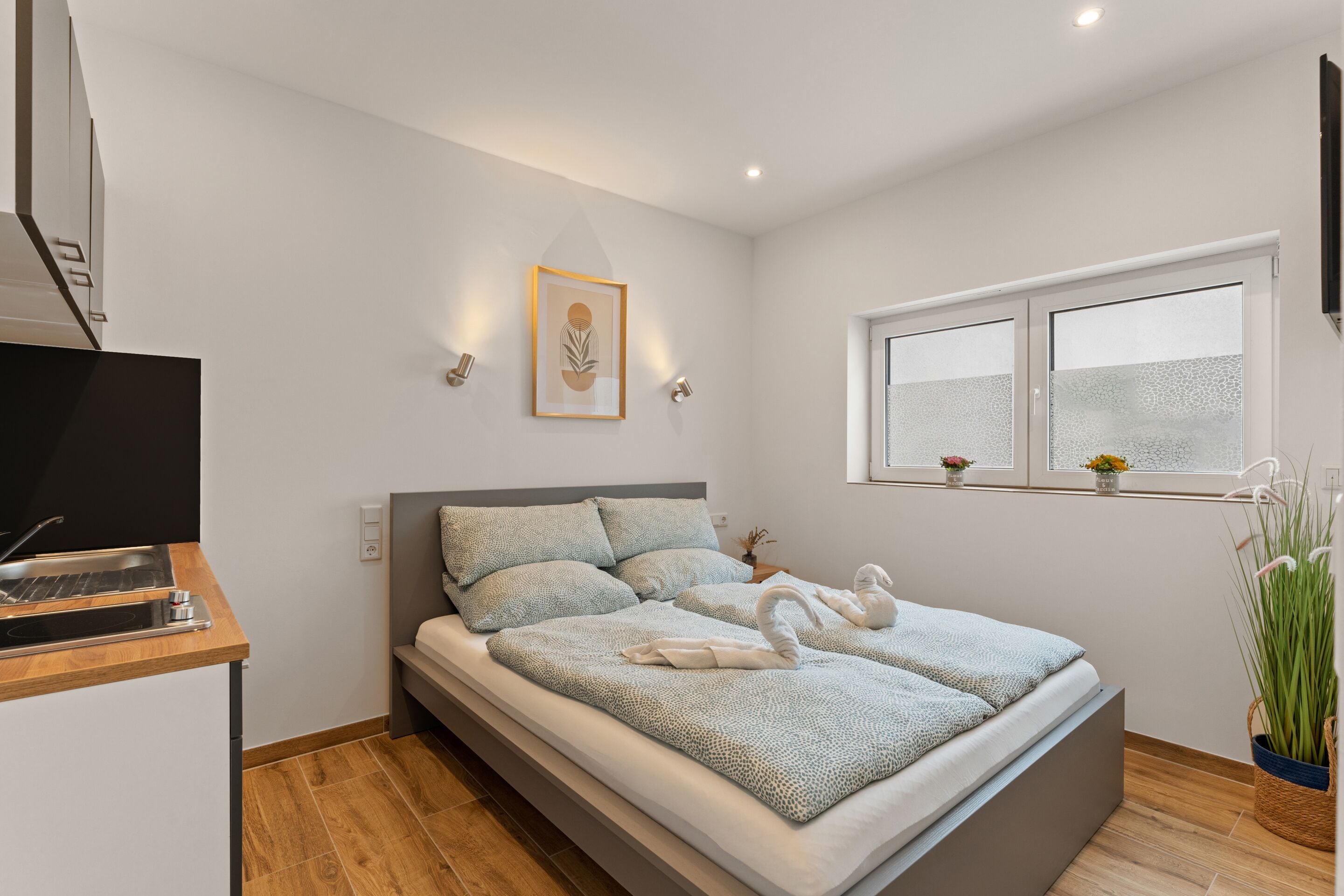 Une chambre à coucher moderne avec un lit, une table de chevet et une fenêtre à vitres dépolies.
