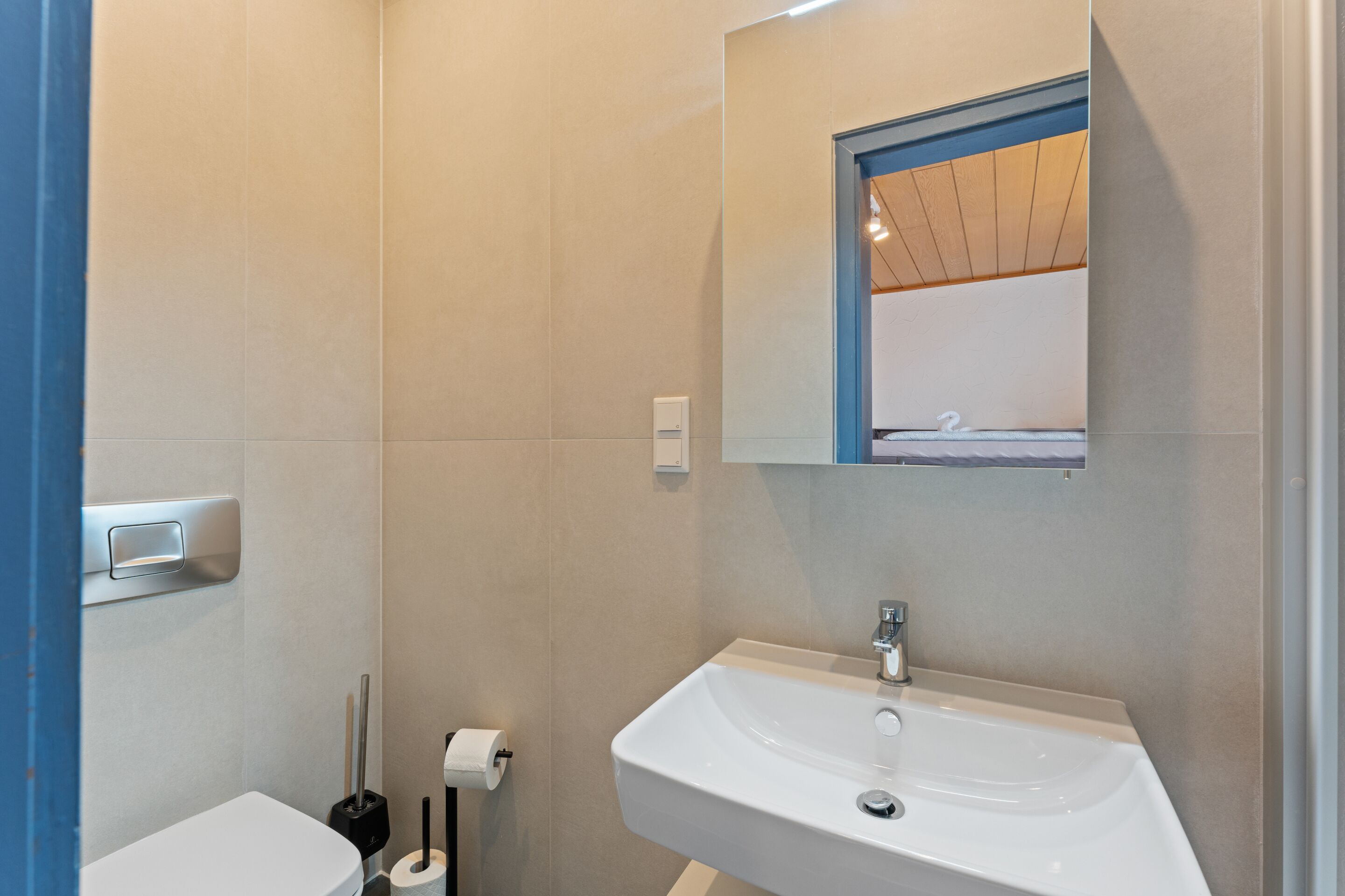 Une salle de bain avec un lavabo blanc, un miroir et des toilettes.