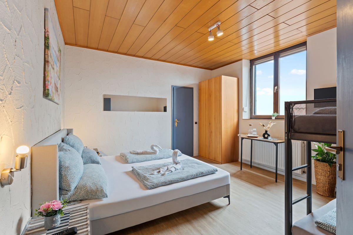A modern bedroom with a bed, bedside table, and a window with a view.