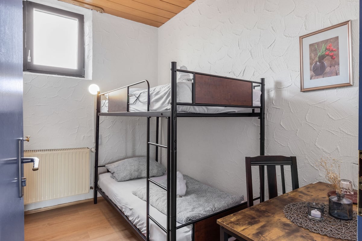 A bunk bed room with a wooden table, a chair, and a radiator.