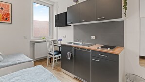 Cocina compacta con horno integrado, un lavamanos y un pequeño comedor con una silla.