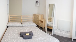 Cozy retreat with a large bed, dresser, and mirror.